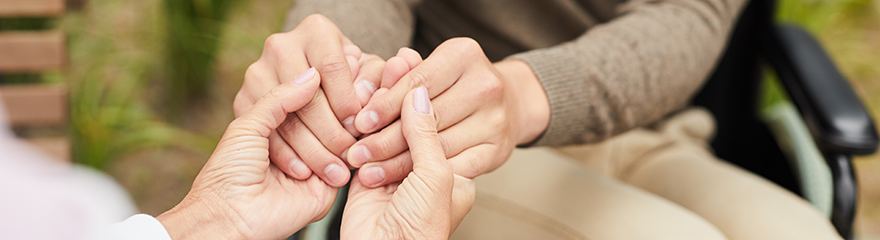 Close up of two people holding hands to show support